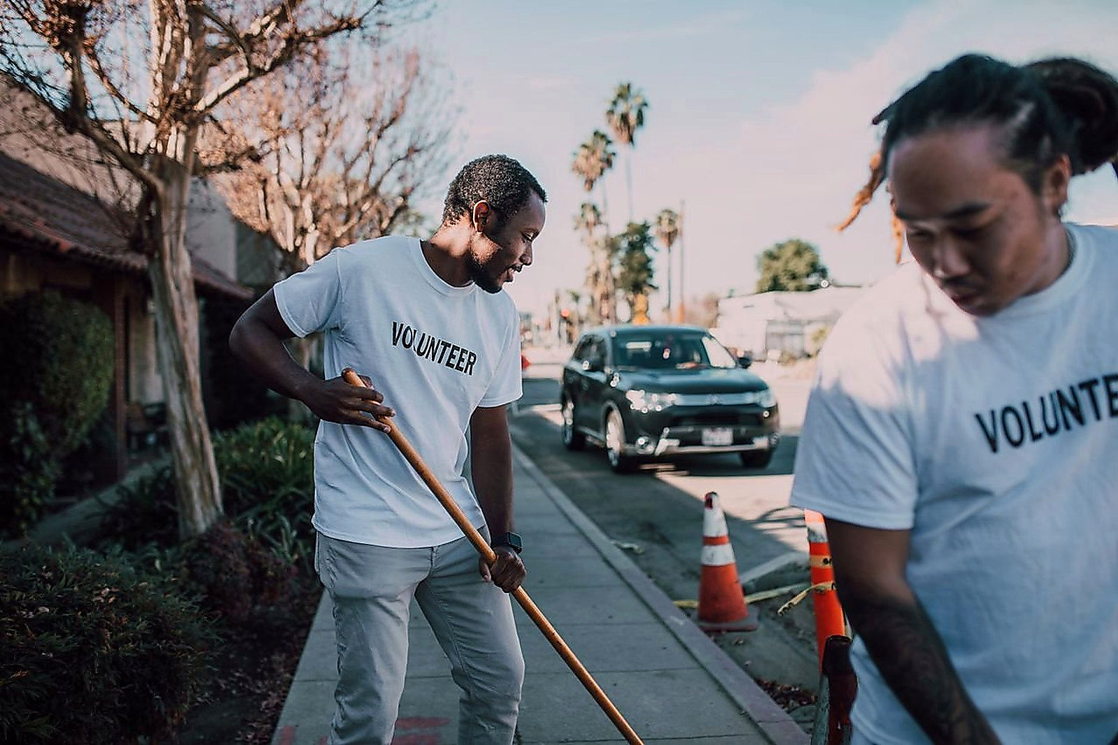 Free Two volunteers working together to clean a sidewalk on a sunny day. Stock Photo